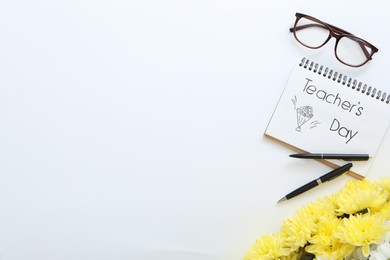 Beautiful flowers, glasses and notebook with words TEACHER'S DAY on white background, flat lay. Space for text