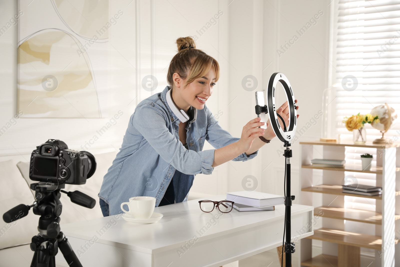 Photo of Blogger preparing for video recording at home. Using ring lamp and smartphone