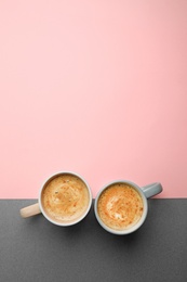 Cups of coffee on color background, top view. Space for text