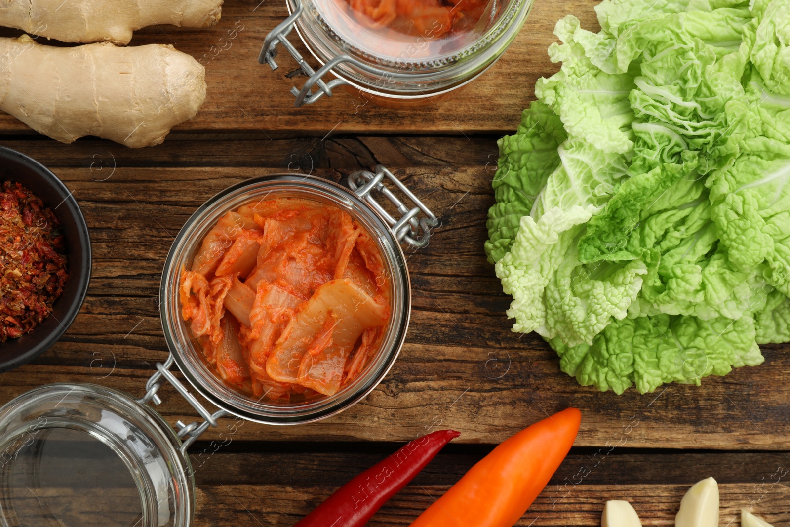 Photo of Delicious kimchi with Chinese cabbage and ingredients on wooden table, flat lay