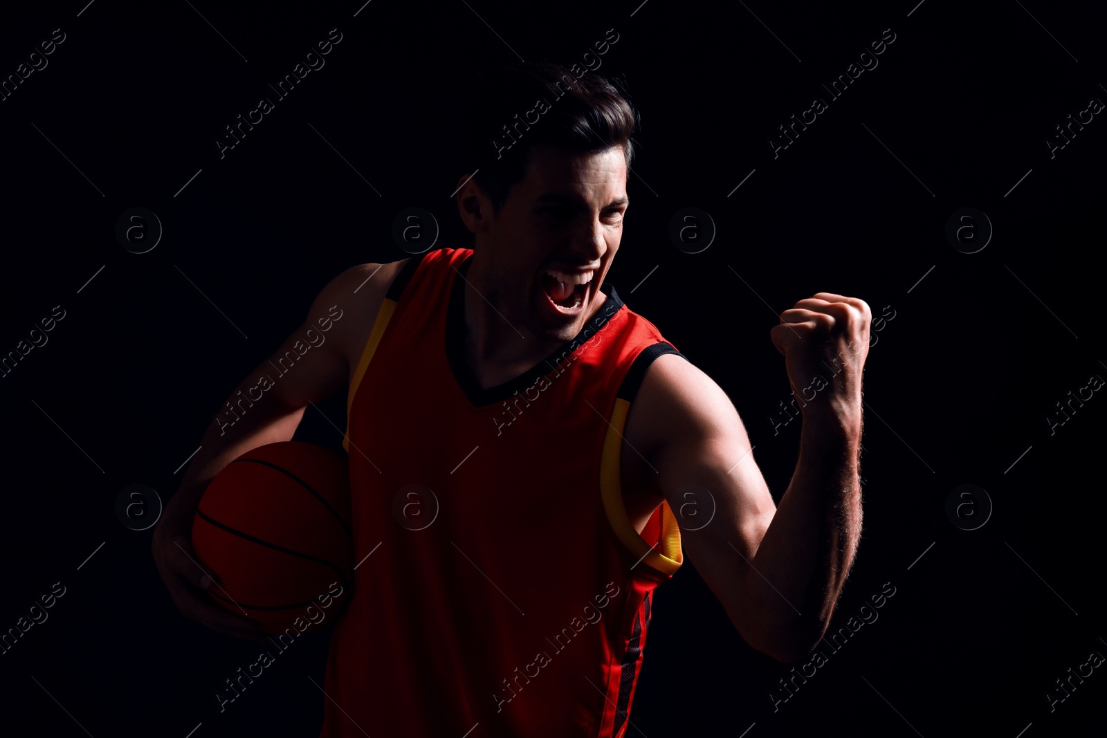 Photo of Basketball player with ball on black background