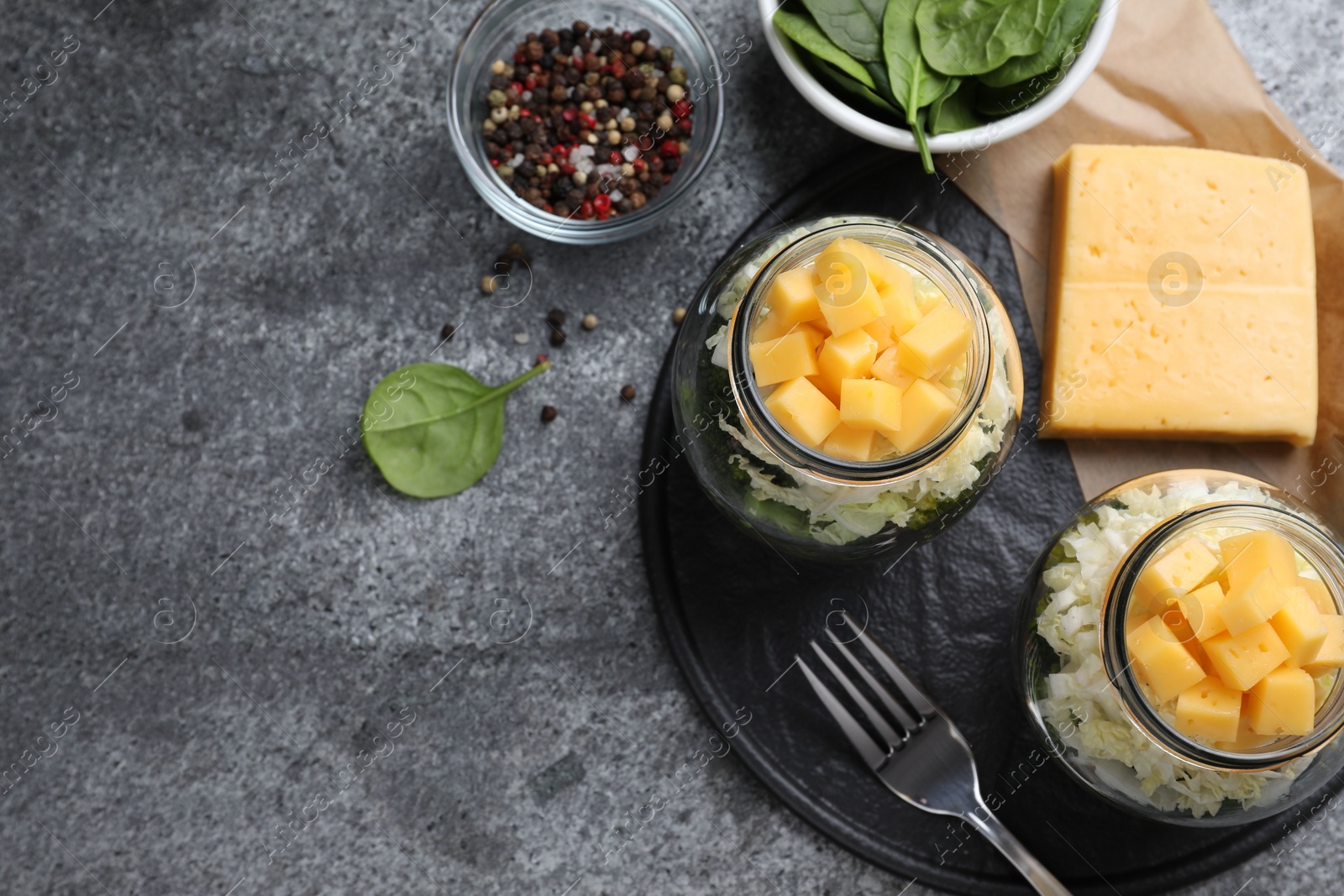 Photo of Healthy salad in glass jars on grey table, flat lay