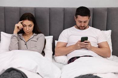 Offended couple ignoring each other after quarrel in bed. Relationship problems