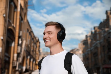 Photo of Smiling man in headphones listening to music outdoors