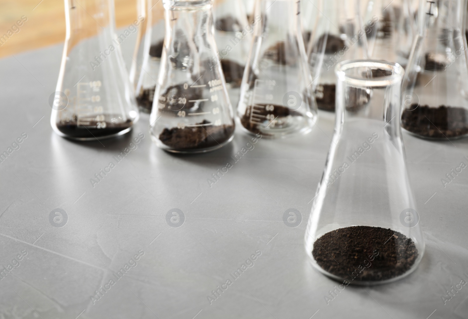 Photo of Glassware with soil samples on grey table. Laboratory research