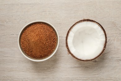Photo of Natural coconut sugar in bowl on white wooden table, flat lay