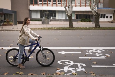 Happy beautiful woman with bicycle on lane in city