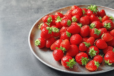 Photo of Plate with ripe strawberries on grey background