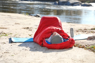 Photo of Male camper lying in sleeping bag on wild beach