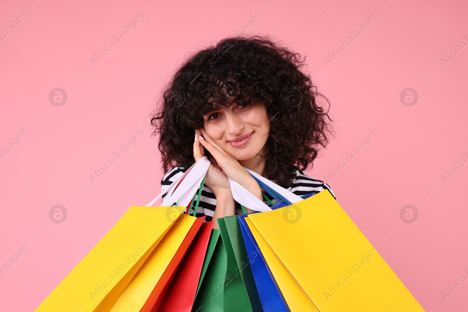 Photo of Happy young woman with shopping bags on pink background