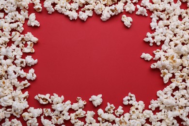 Photo of Frame made of tasty popcorn on red background, flat lay and space for text