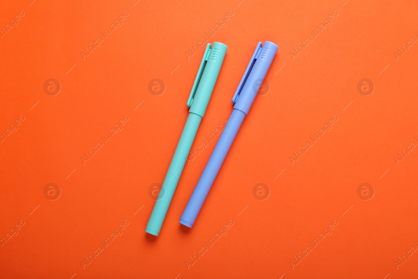 Photo of Two colorful markers on orange background, flat lay