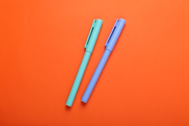 Photo of Two colorful markers on orange background, flat lay