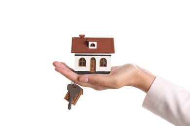 Real estate agent holding house model and key on white background