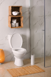 Photo of White toilet bowl near marble wall in bathroom