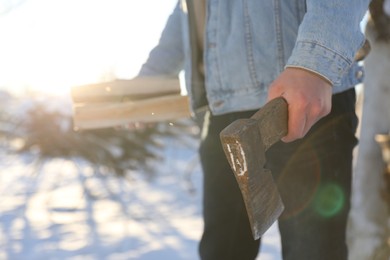 Photo of Man with axe and wood outdoors on sunny winter day, closeup. Space for text