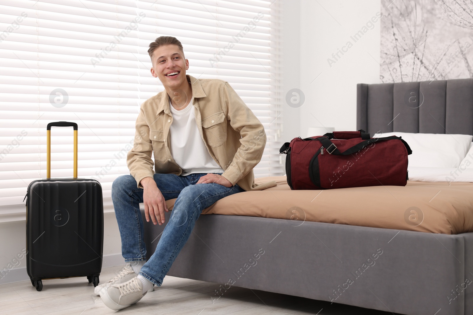 Photo of Smiling guest relaxing on bed in stylish hotel room