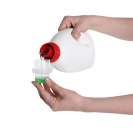 Photo of Woman pouring fabric softener from bottle into cap on white background, closeup