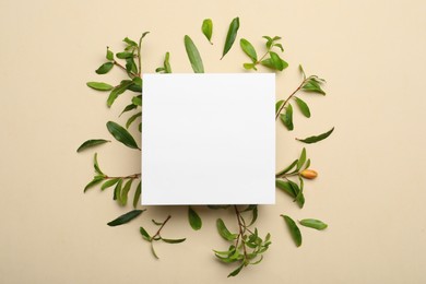 Photo of Flat lay composition with pomegranate branches and blank card on beige background. Space for text