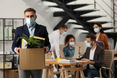 Upset dismissed man carrying box with stuff in office, space for text