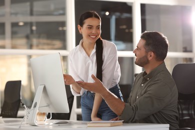 Photo of Colleagues working on computer at desk in office