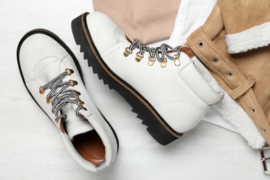 Photo of Pair of stylish boots and clothes on white wooden table, flat lay