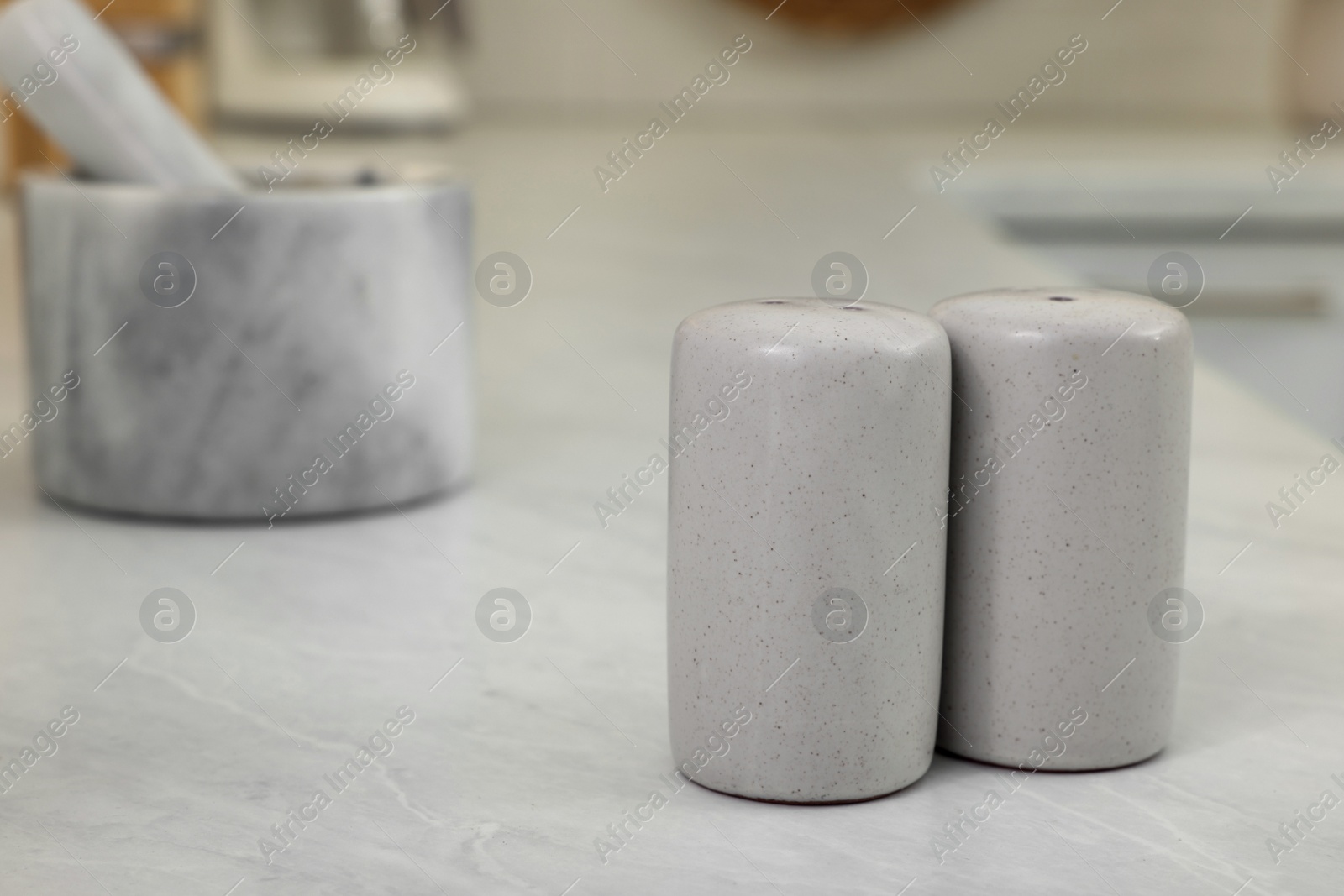 Photo of Ceramic salt and pepper shakers on white table in kitchen. Space for text