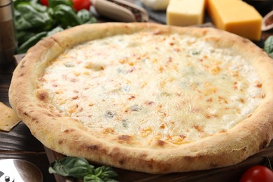 Photo of Delicious cheese pizza and ingredients on wooden table, closeup