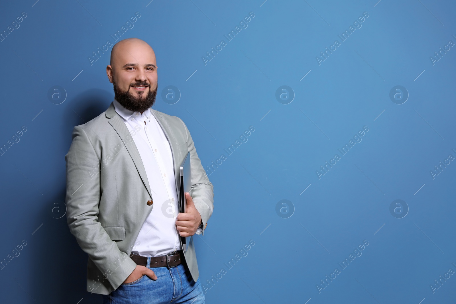 Photo of Portrait of confident young businessman with laptop on color background