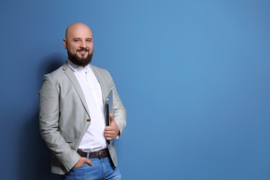 Portrait of confident young businessman with laptop on color background