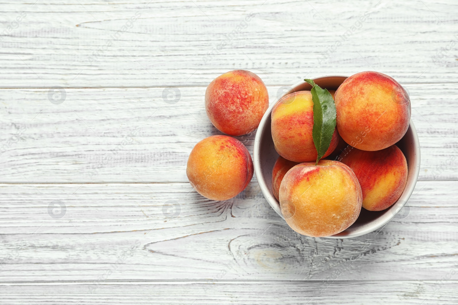 Photo of Bowl with delicious ripe peaches on wooden background, top view