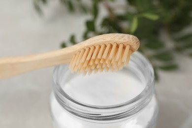 Bamboo toothbrush and jar of baking soda on table, closeup