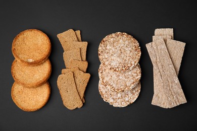 Photo of Rye crispbreads, rice cakes and rusks on black background, flat lay