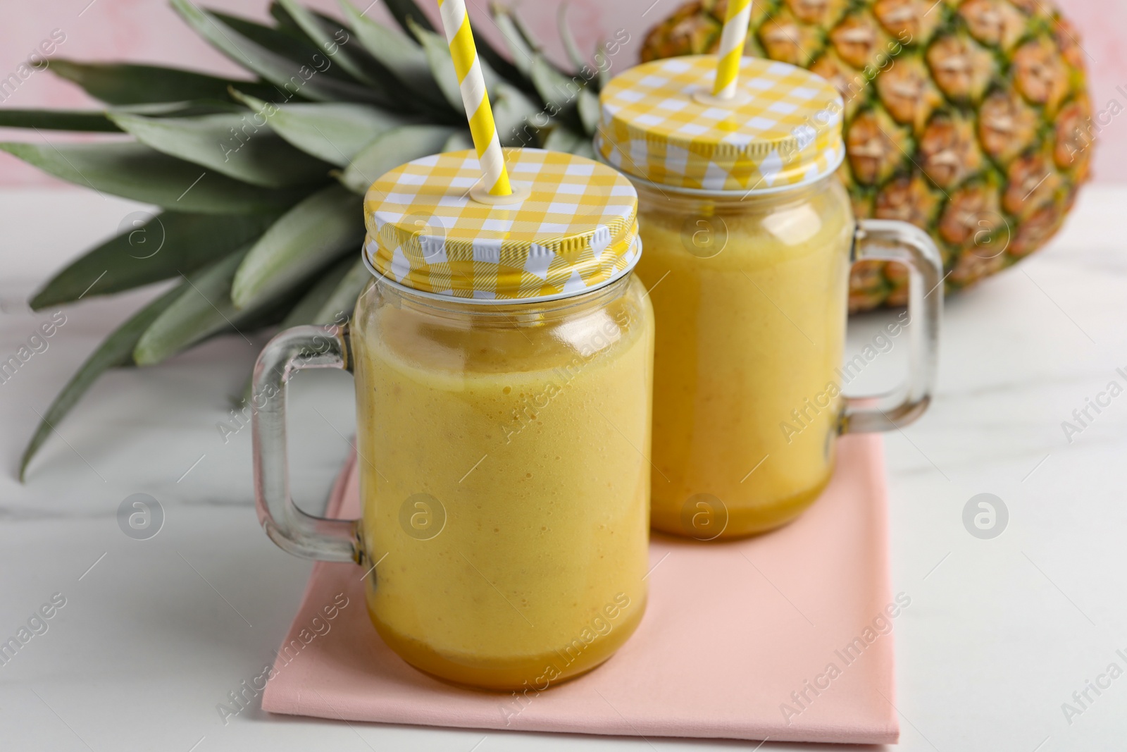 Photo of Tasty pineapple smoothie and fruit on white table