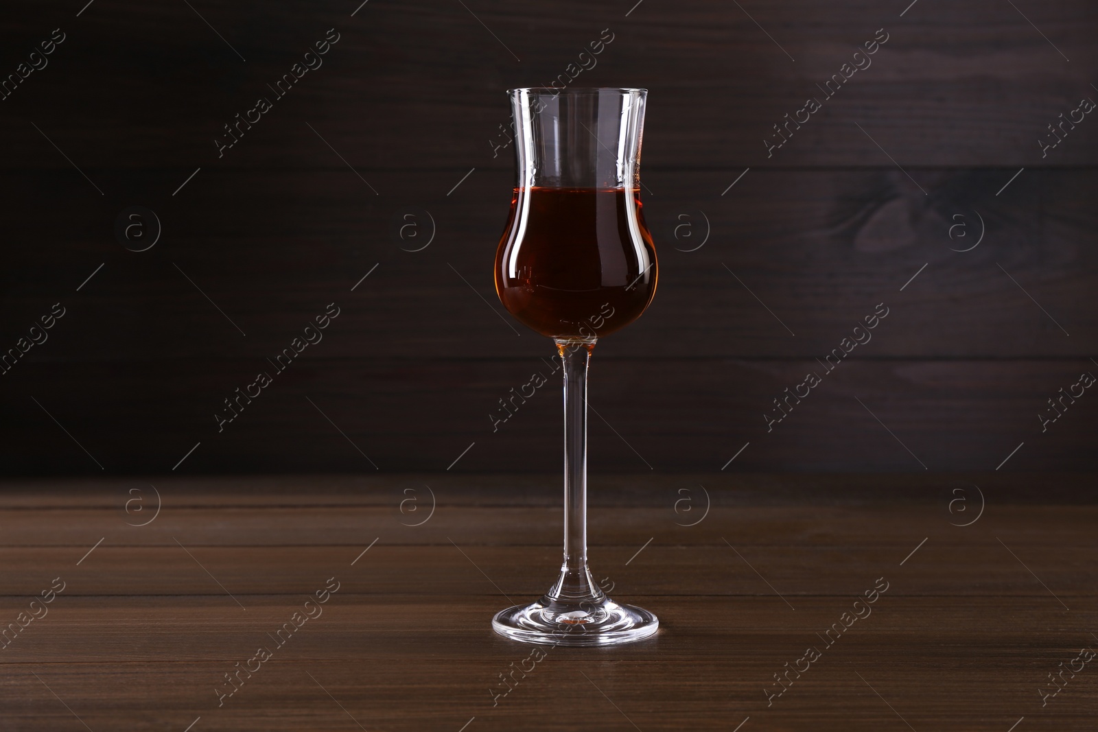 Photo of Delicious liqueur in glass on wooden table
