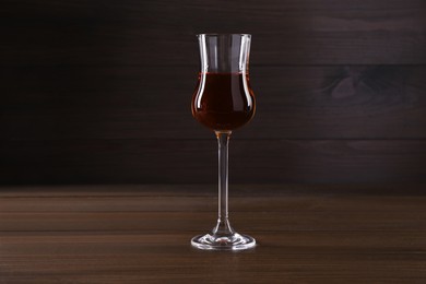 Delicious liqueur in glass on wooden table