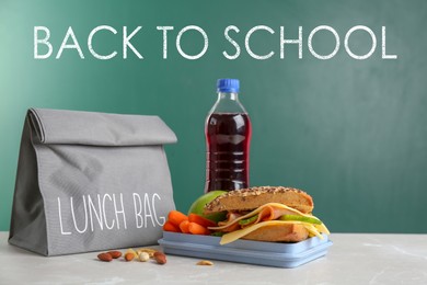 Lunch box with appetizing food and bag on table near chalkboard