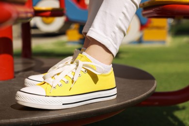 Photo of Woman wearing yellow classic old school sneakers outdoors, closeup