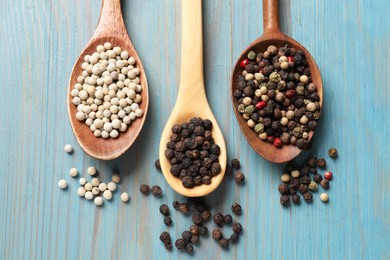 Photo of Aromatic spice. Different peppers in spoons on light blue wooden table, flat lay