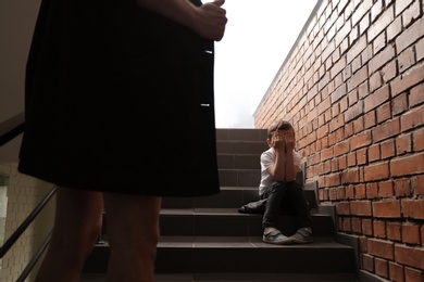 Male exhibitionist opening his coat in front of scared little boy indoors. Child in danger