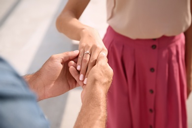 Photo of Lovely couple with beautiful ring after engagement outdoors, closeup