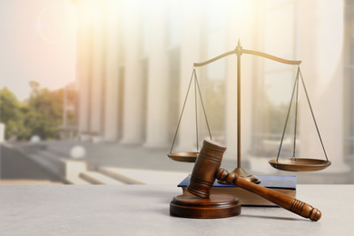 Image of Wooden gavel, scales of justice and book on table against beautiful cityscape, space for text 