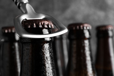 Opening bottle of tasty cold beer on grey background, closeup. Space for text