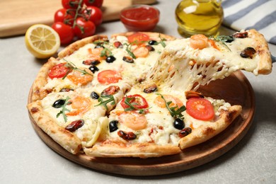 Photo of Taking slice of cheese pizza with seafood at grey table, closeup