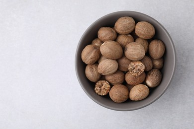Nutmegs in bowl on light table, top view. Space for text