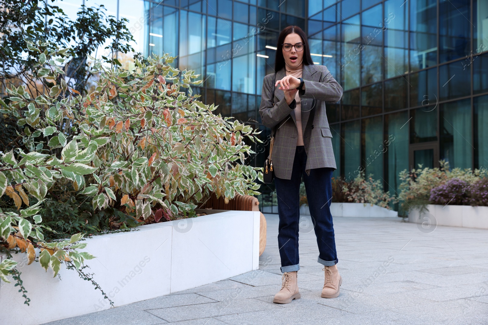 Photo of Emotional woman checking time on watch outdoors. Being late concept