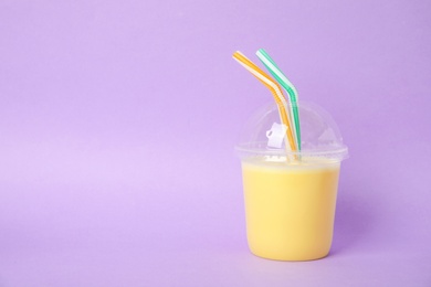 Photo of Plastic cup of tasty milk shake and space for text on color background