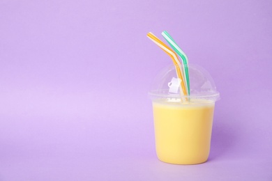 Plastic cup of tasty milk shake and space for text on color background