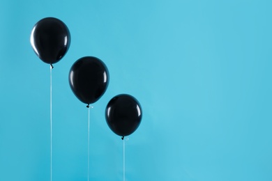 Photo of Black balloons on blue background, space for text. Halloween party