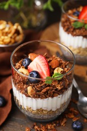 Photo of Tasty granola with berries, nuts, yogurt and chia seeds in glass on table, closeup